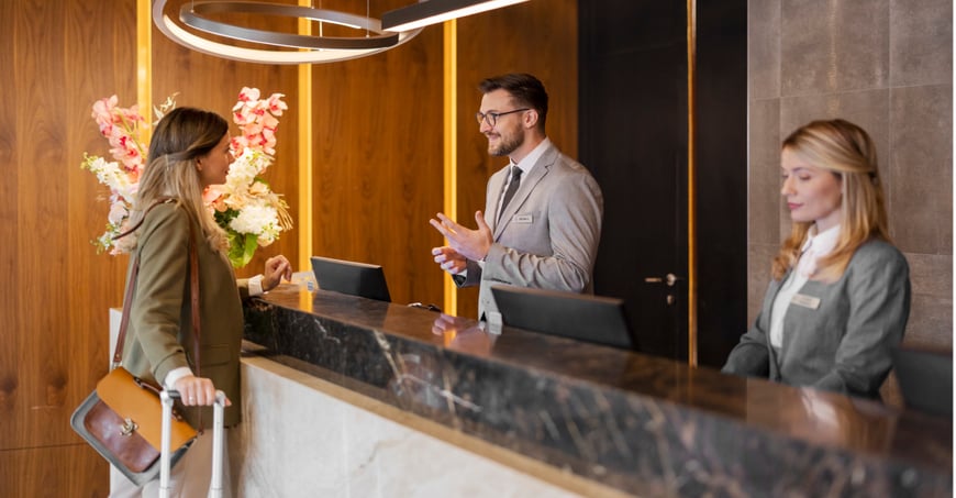 traveller checking in to a concierge managed by two hotel employees