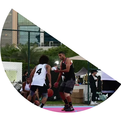 Two friends playing basketball outdoors at one of JLT's basketball facilities